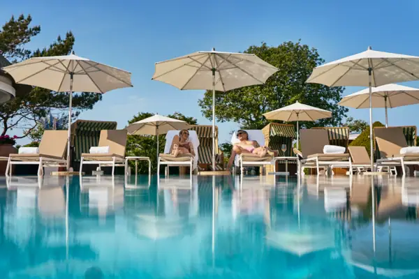 Un gruppo di persone sedute su sedie accanto a una piscina.