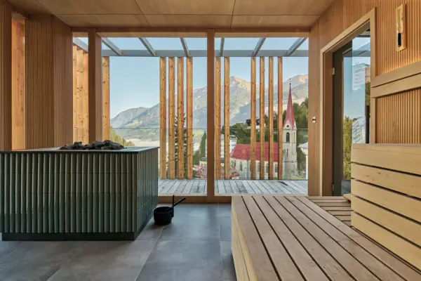 Ein Raum mit Sauna und Blick auf Berge und eine Kirche.