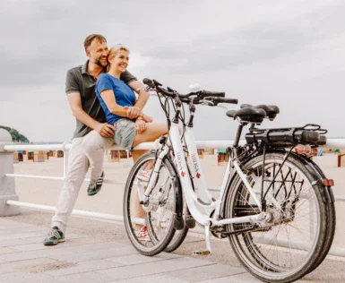 Uomo e donna seduti su una ringhiera accanto a delle biciclette.