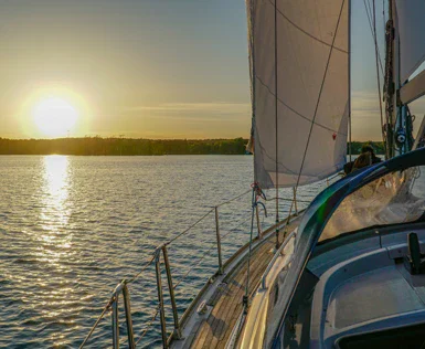 Barca a vela che naviga su un lago al tramonto.