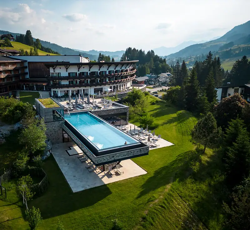 Piscina all'aperto di un hotel con vista sugli alberi e sul cielo.