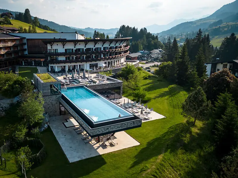 Ein Outdoor Infinity Pool in einem Hotel mit Blick auf Bäume und Himmel.