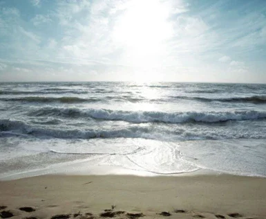 Onde che si infrangono sulla spiaggia con cielo nuvoloso.