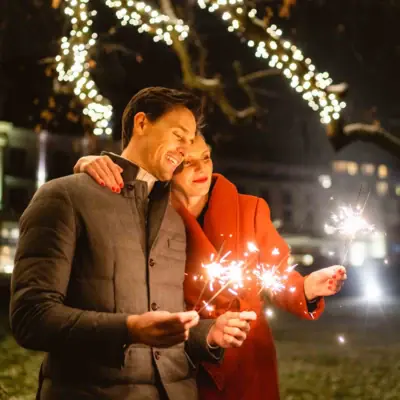 Un uomo e una donna tengono in mano delle candeline magiche.