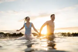 Un uomo e una donna si tengono per mano nell'acqua.