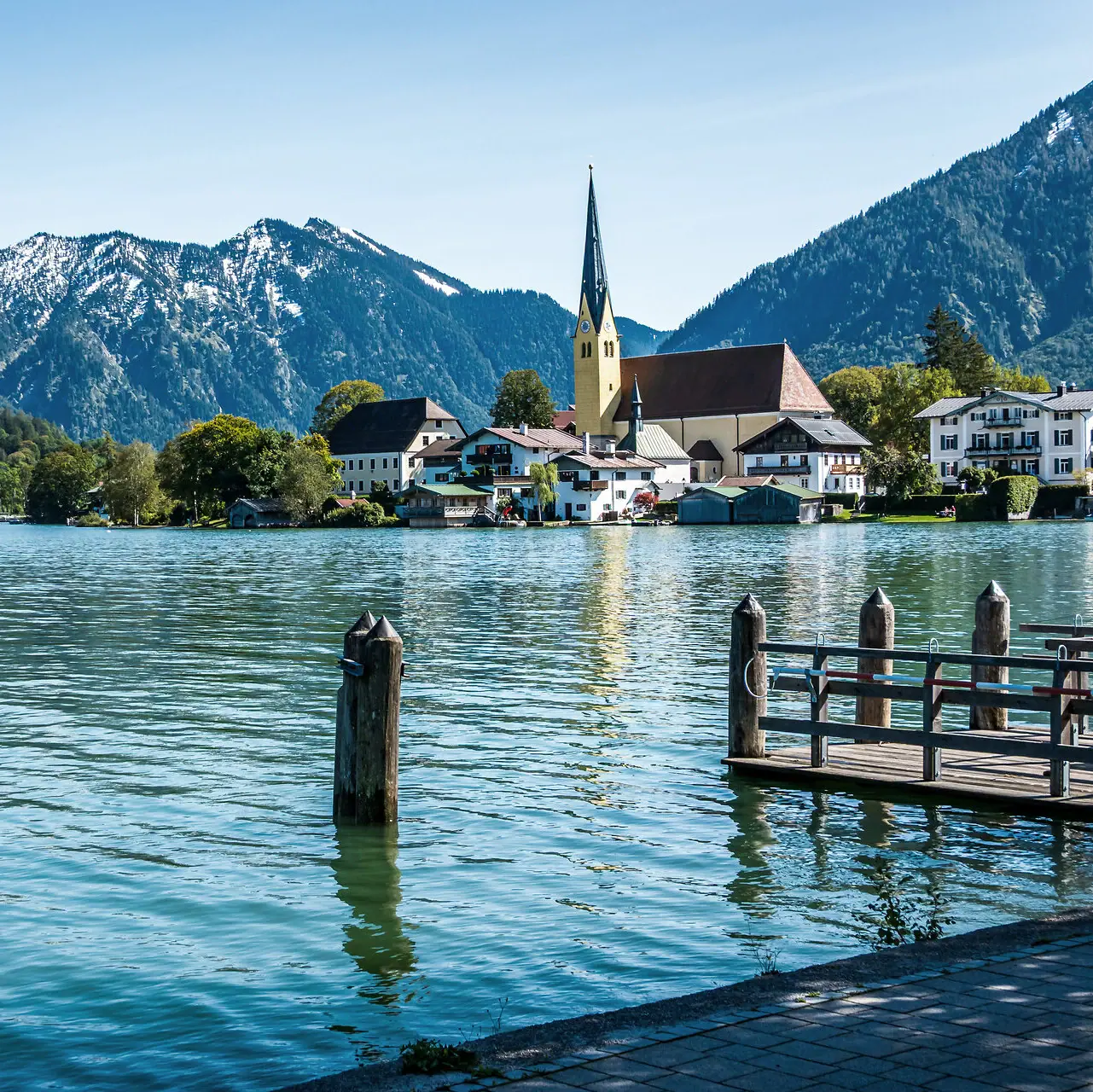 Un lago con una chiesa e le montagne sullo sfondo.