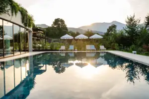 Una piscina con sedie a sdraio e ombrelloni sullo sfondo.