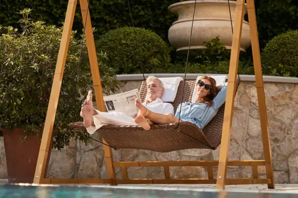 Un uomo e una donna sono sdraiati su un'amaca a bordo piscina.