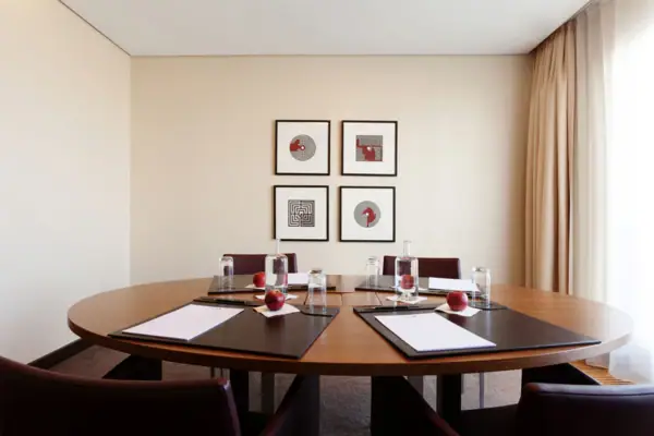 In einem kleinen Meetingraum steht ein ovaler Tisch mit 4 Sesseln.