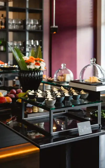 Tavolo da buffet con una selezione di cibi e bevande in una sala interna.