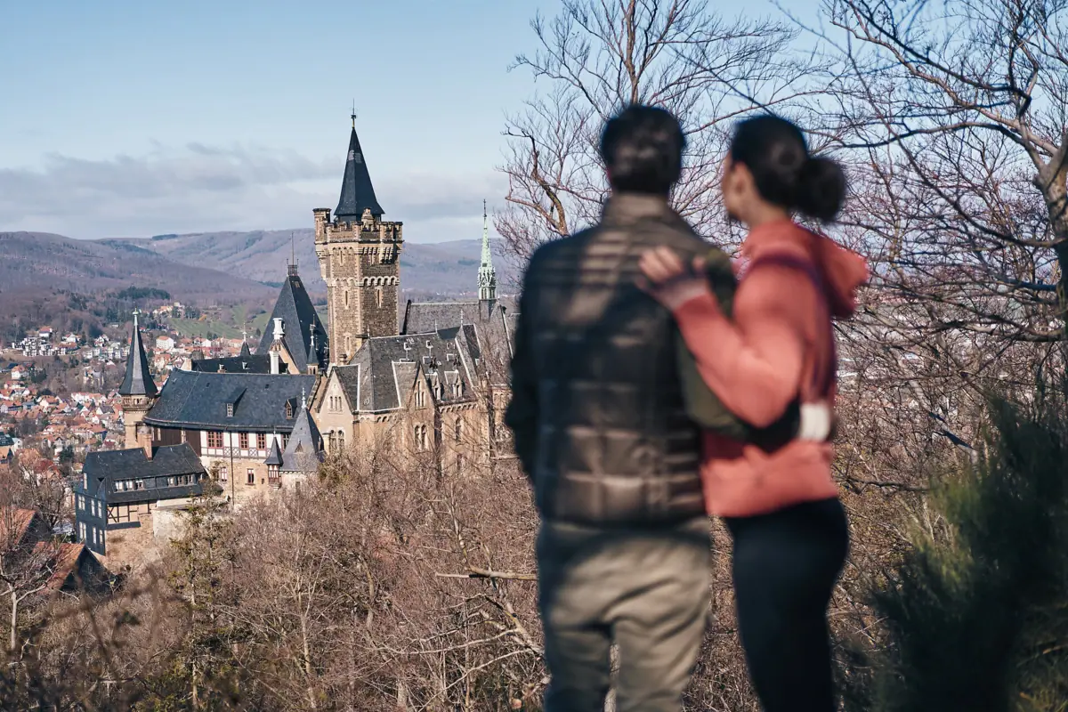 Un uomo e una donna sono in piedi su una collina e guardano verso il castello di Wernigerode.