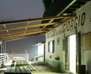 Edificio con panchina e tavolo all'aperto sotto il cielo notturno.