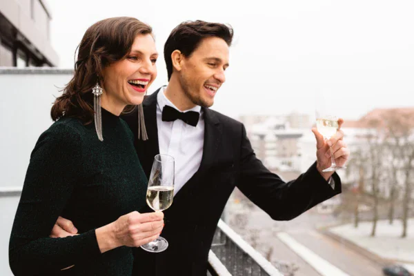 Uomo e donna sorridenti che tengono bicchieri di vino all'aperto.