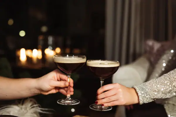 Anstoßen mit Drinks Hände halten Cocktailsgläse mit brauner Flüssigkeit