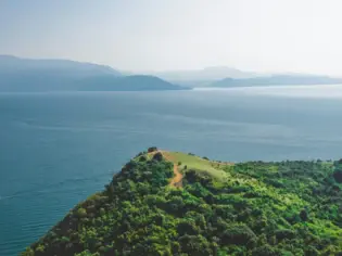 Collina verde con alberi e specchio d'acqua.