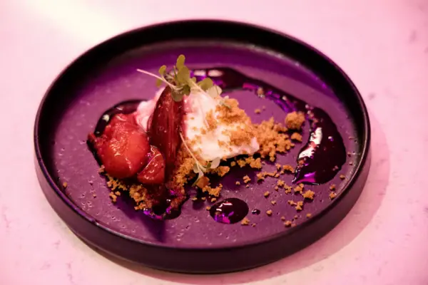 Un piatto da dessert guarnito con frutta e granella.