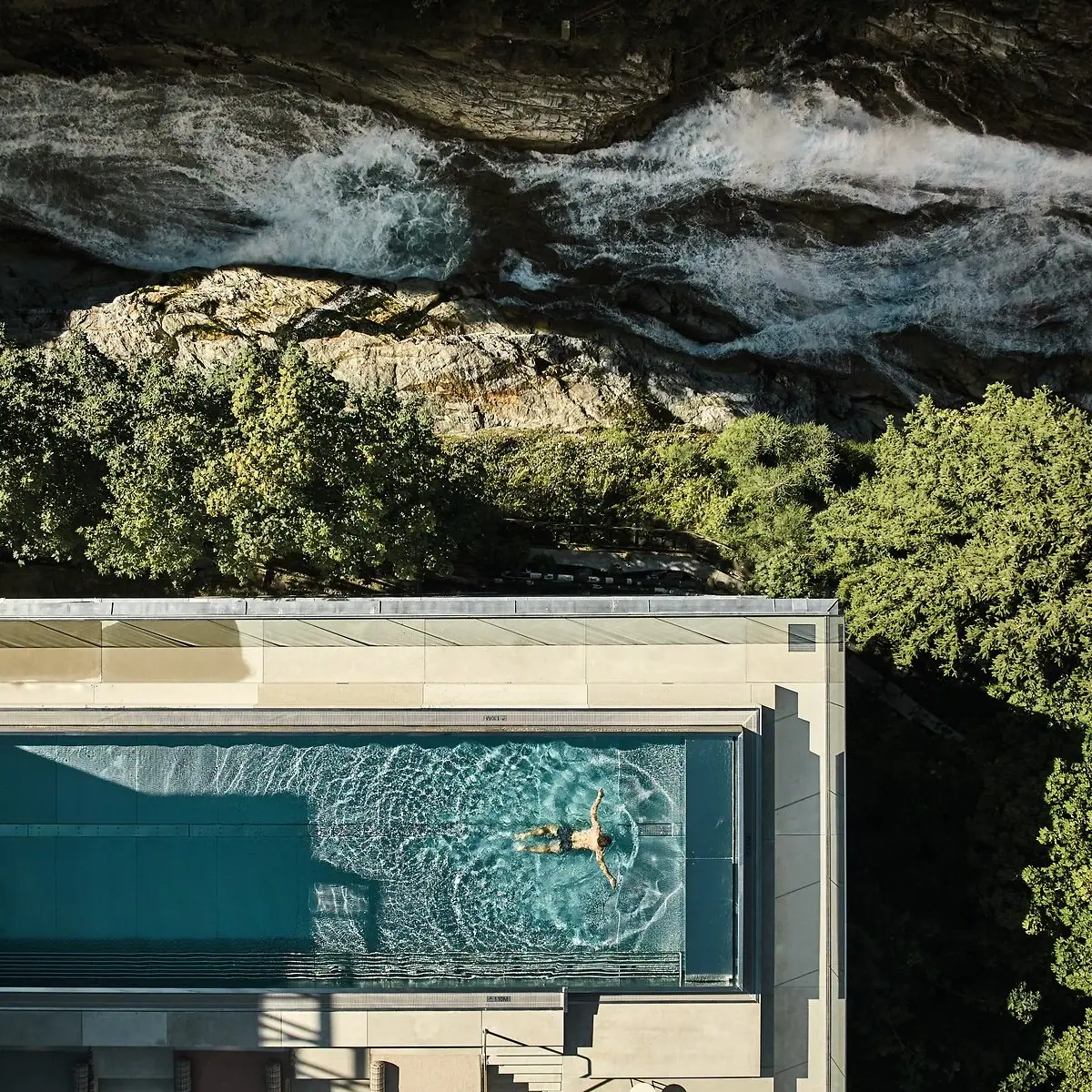 Una persona nuota nella piscina dell'A-ROSA Straubinger Grand Hotel Bad Gastein, accanto alla cascata di Gastein.