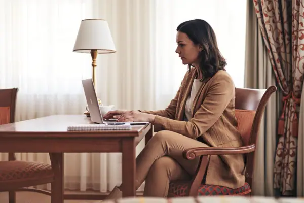 Frau sitzt an einem Schreibtisch und benutzt einen Laptop.