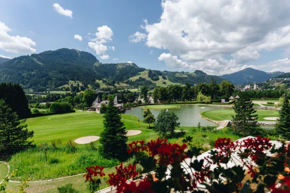 Campo da golf con lago e montagne sullo sfondo.