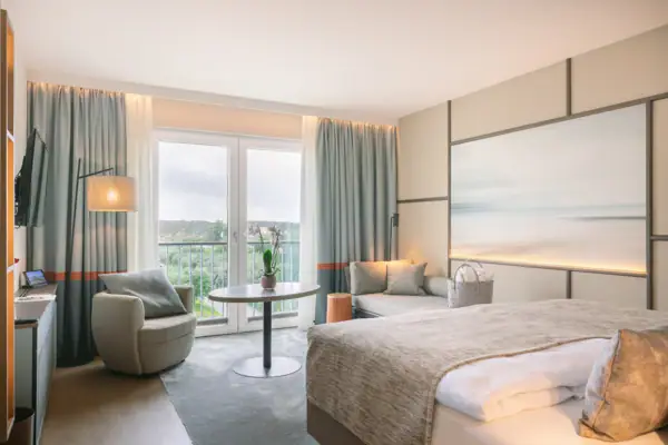 Zimmer im A-ROSA Sylt Ein Hotelzimmer mit einem Bett, einemSchreibtisch und einem gemütlichen Sessel.