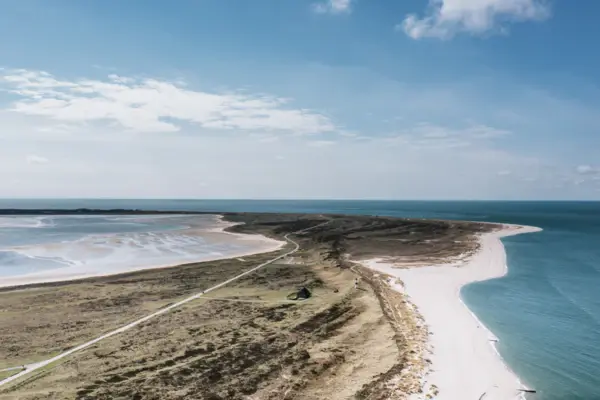 Spiaggia sabbiosa con vista sull'oceano e cielo nuvoloso.