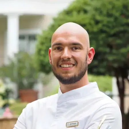 Il capo cuoco Jan Kruse Un uomo sorridente in camice bianco.