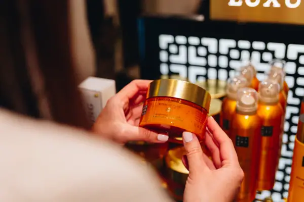 SPA Shop Eine Person hält ein Glas mit Creme.