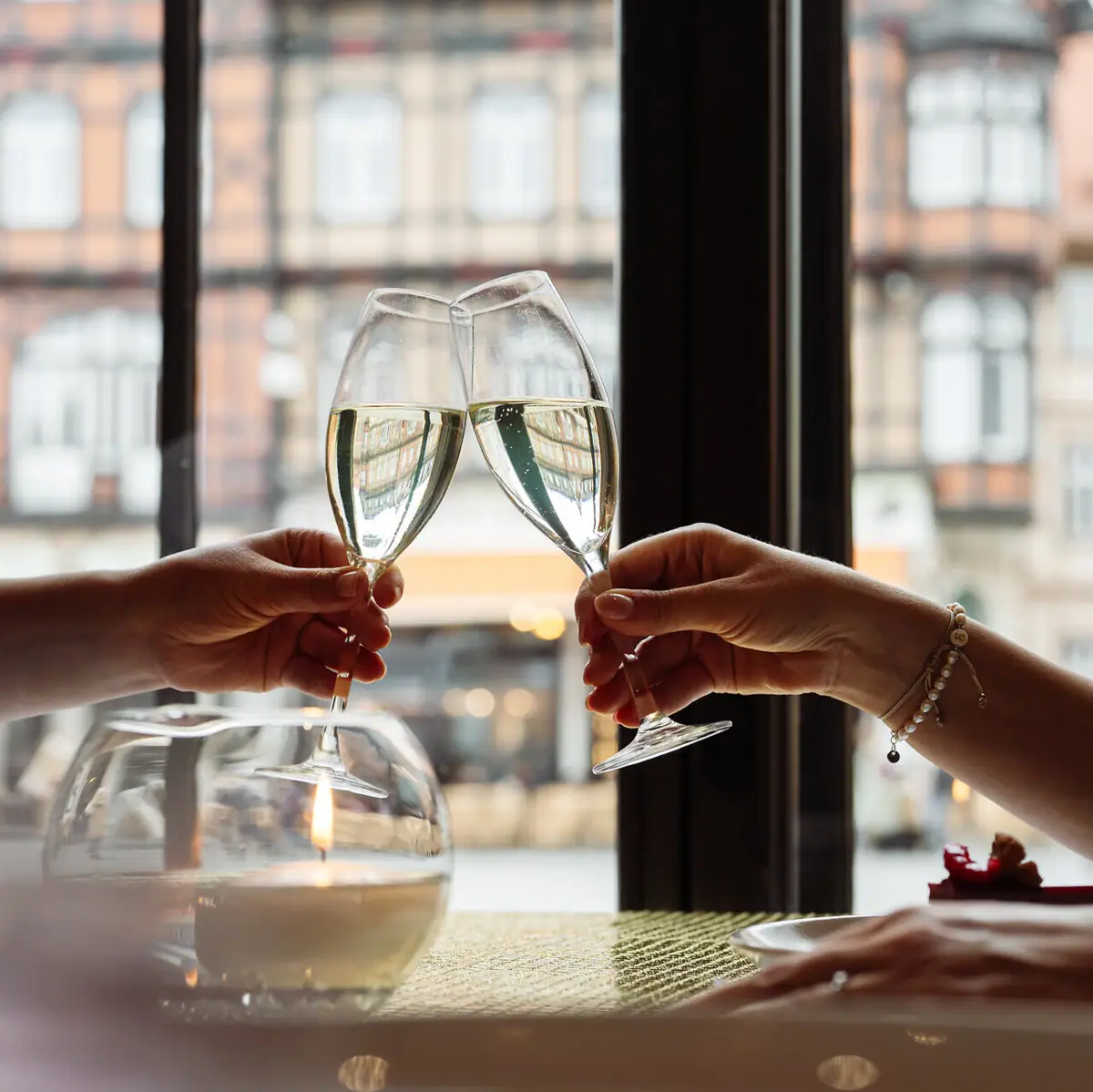 Due mani brindano con i calici di vino.