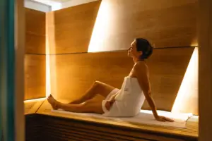 Sauna Una donna avvolta in un asciugamano è seduta su una panchina.