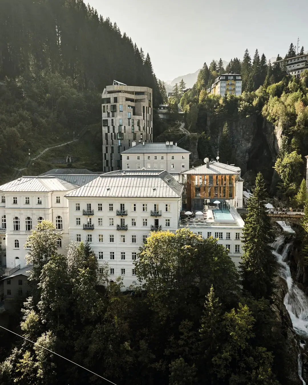 Un gruppo di edifici con alberi e montagne sullo sfondo.