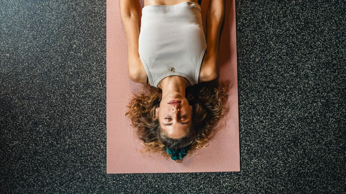 Una donna è sdraiata su un tappetino da yoga.