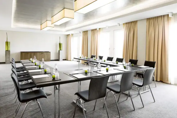 In einem Veranstaltungsraum stehen einige Tische und Stühle in U-Form.