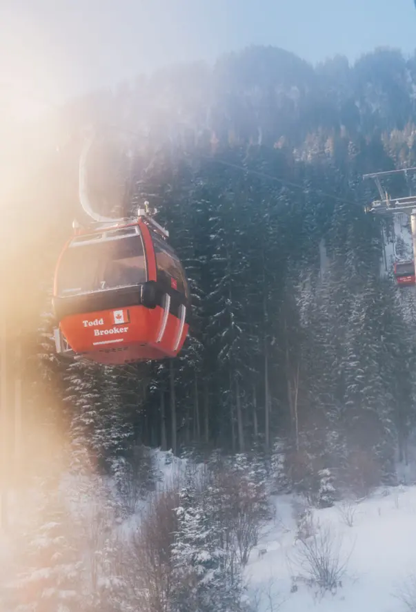 Gondola su una funivia coperta di neve, con alberi innevati intorno in un ambiente montano.