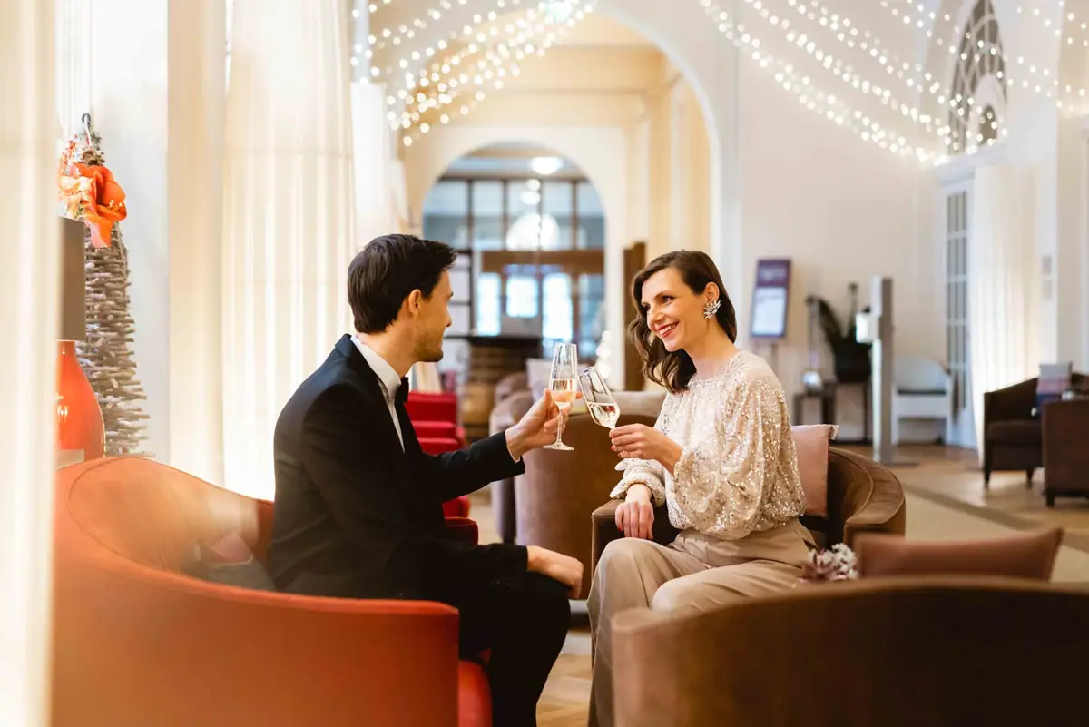 Anstoßen Ein Mann und eine Frau sitzen in Sesseln und stoßen mit Sektgläsern an.