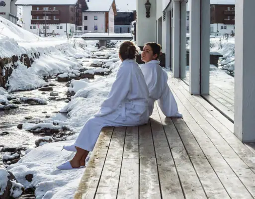 Due donne sono sedute su una veranda davanti a un edificio all'aperto.
