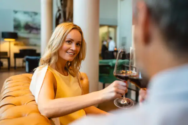 Frau hält ein Weinglas und lächelt.