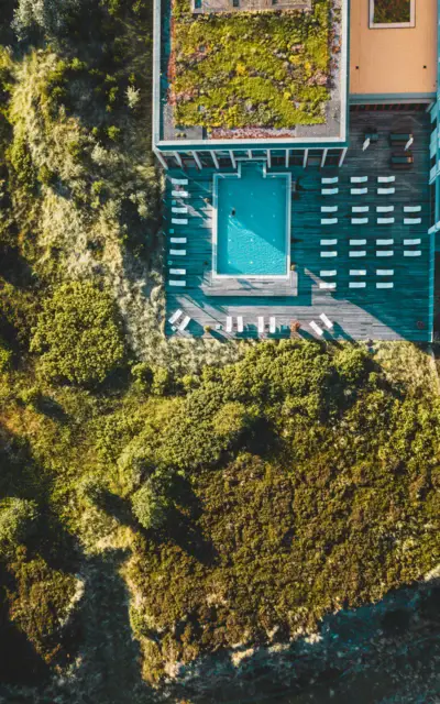 Piscina con sedie e un edificio circondato da alberi.