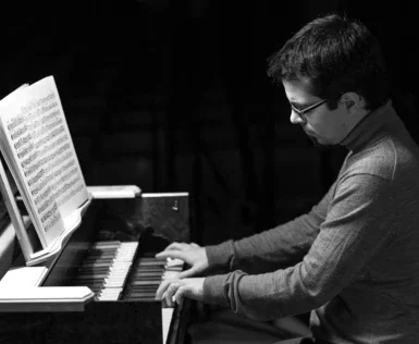 Uomo che suona un pianoforte in bianco e nero.