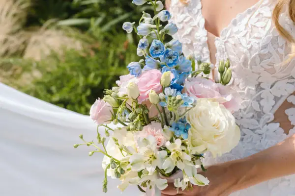 Una donna con un vestito bianco tiene in mano un mazzo di fiori.