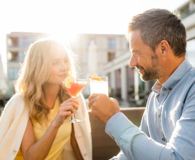 Uomo e donna all'aperto che tengono dei bicchieri con bevande.