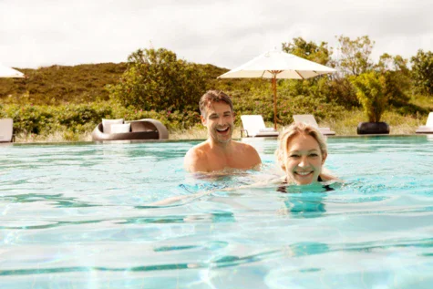 Uomo e donna che nuotano in una piscina all'aperto.