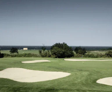 Campo da golf con bunker di sabbia e alberi.