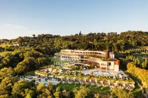 Un edificio con una piscina, circondato da alberi.