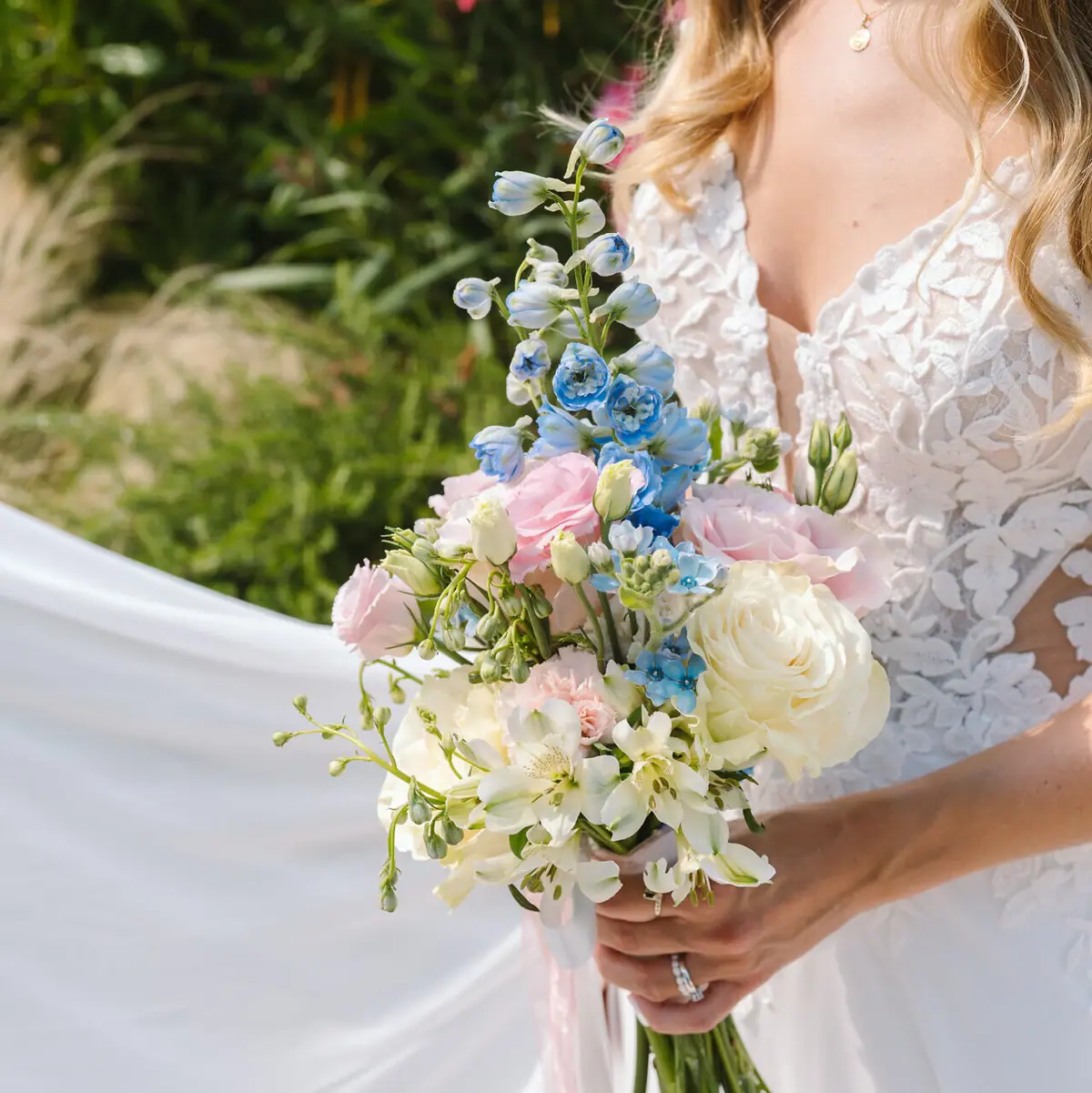 Una donna in abito da sposa bianco tiene in mano un mazzo di fiori durante un matrimonio sul lago di Tegernsee.