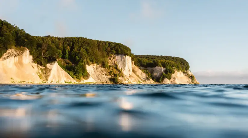 Le scogliere di gesso di Rügen si protendono nel blu scintillante del Mar Baltico. Le scogliere sono ricoperte da fitte foreste di faggio verde scuro.