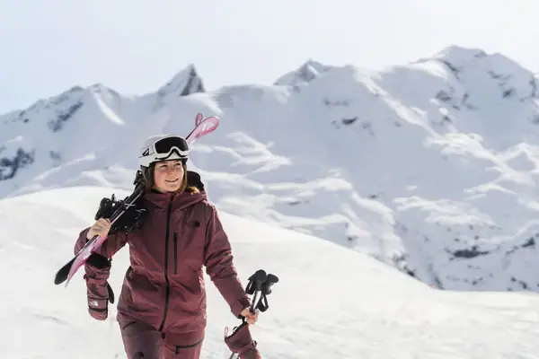 Frau in Skianzug mit Skistöcken und Helm im Schnee