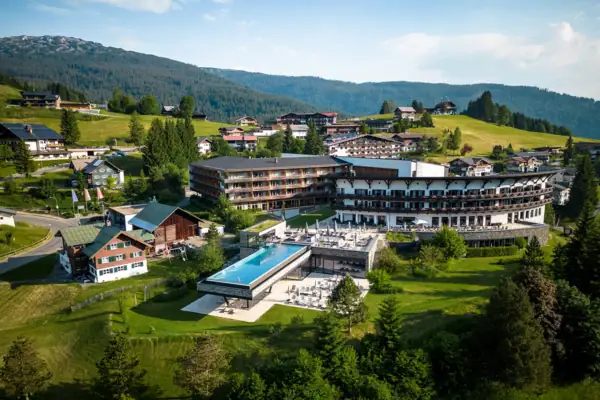 Das A-ROSA Ifen Hotel im Kleinwalsertal mit großen Outdoor-Pool inmitten eines Berg-Dorfes.