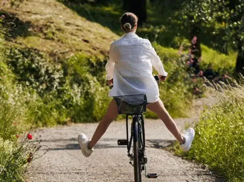 Donna in bicicletta su un sentiero.