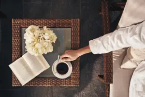 Una persona tiene in mano una tazza di caffè e un libro.