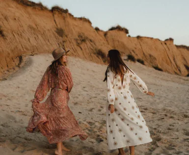 Due donne camminano su una spiaggia sabbiosa.